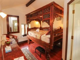 A bedroom with a carved wooden bed and a table at The School House in Penrith