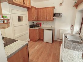 A kitchen with wooden cabinets and appliances at The School House in Patterdale near Glenridding