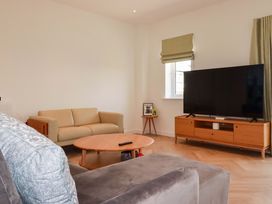 A living room with a sofa and television at Edens in Penwithick