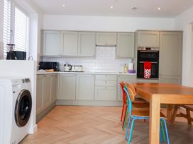 A kitchen with a washing machine and dining table at Edens in Penwithick