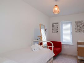 A bedroom with a bed and a red sofa at Edens in Penwithick