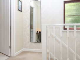 A hallway with a mirror and stair railing at Marldon Mews in Marldon