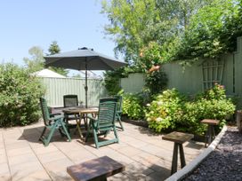 A garden with a table and chairs under an umbrella at Marldon Mews in Marldon