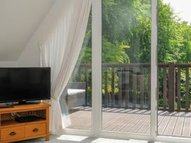 A living room with a television and sliding door to the deck at 9 Honicombe Park in Callington