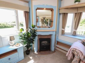 A living room with a fireplace and plant at Mor a Mynydd in Pwllheli
