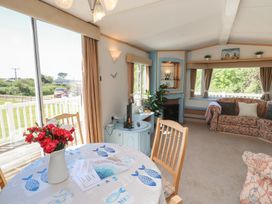 A living room with a table, chairs, sofa and television at Mor a Mynydd in Pwllheli