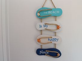 A decorative sign with flip flops and the words The Beach Is My happy place