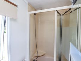 A shower with glass door in a bathroom at Mor a Mynydd Pwllheli