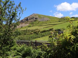A hillside with a rock formation and greenery at Mor a Mynydd in Pwllheli