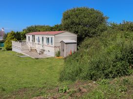 A mobile home with a deck and a shed in an outdoor area at Mor a Mynydd in Pwllheli