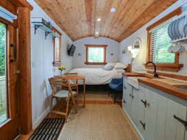 A bedroom with a bed, table, and kitchen area at Ardwyn in Pwllheli