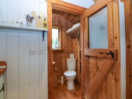 A bathroom featuring a toilet and wooden shelves at Ardwyn Pwllheli
