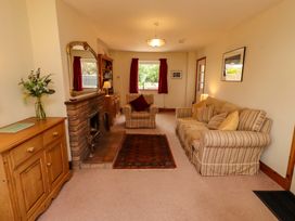 A living room with a sofa, armchair, and fireplace at Sarah's Cottage