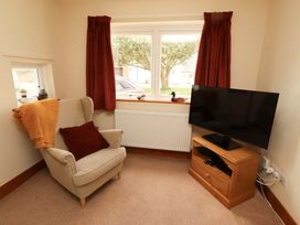 A living room with an armchair and a television at Sarah's Cottage