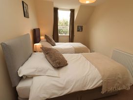 A bedroom with two single beds and a window at Sarah's Cottage