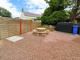 A garden with a table, benches, and bins at Sarah's Cottage