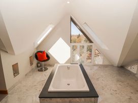 A bathroom with a bathtub and chair at Midways in Windermere