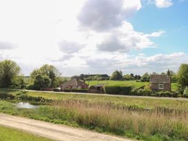 A house with trees and a water body in the background at Laurel in Littleport