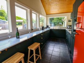 A kitchen with bar stools and windows at Bull Rush Cabin in Carwinley near Longtown