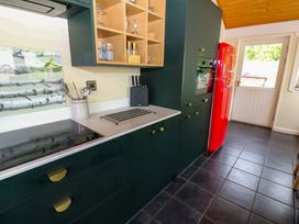 A kitchen with cabinets and a red refrigerator at Bull Rush Cabin in Carwinley near Longtown