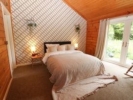 A bedroom with a bed and nightstand at Bull Rush Cabin Carwinley near Longtown