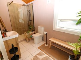 A bathroom with shower, toilet, sink and plant at Bull Rush Cabin in Carwinley near Longtown