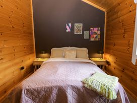 A bedroom with a bed, bedside tables, and wall art at Bull Rush Cabin in Carwinley near Longtown