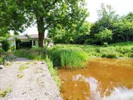 A house with a pond and greenery at Bull Rush Cabin in Carwinley near Longtown