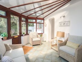A conservatory with seating and plants at Bryn Llifon in Pentraeth