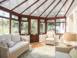 A conservatory with seating and plants at Bryn Llifon in Pentraeth