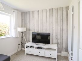 A living room with a television and lamp at Bryn Llifon in Pentraeth