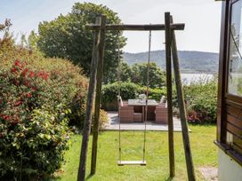 A garden with a swing and outdoor furniture at Bryn Llifon in Pentraeth
