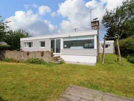A house with a garden and swing at Red Wharf Retreat near Red Wharf Bay