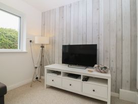 A living room with a TV and lamp at Red Wharf Retreat in Red Wharf Bay near Benllech