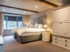 A bedroom with a bed, nightstand, wardrobe, and windows at Prospect House in Windermere