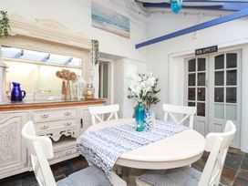 A dining room with a round table and white chairs at Stones Throw in Mevagissey