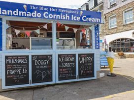 An ice cream stall with menu boards and an employee at The Blue Hut in Mevagissey