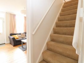 A staircase leading to the upper floor next to a living room with a sofa and coffee table at 19 Covert Road in Reydon