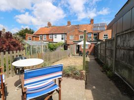 A garden with a table and chairs overlooking a greenhouse at 19 Covert Road in Reydon