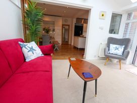 A snug with a red sofa, a chair, and a table at 29 Bincleaves Road Weymouth