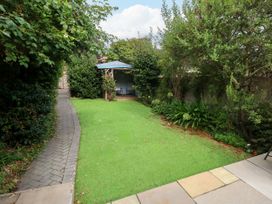 A garden with grass and a pathway leading to a patio at 29 Bincleaves Road Weymouth