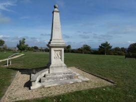 A monument with steps and plaque in a park setting at Coast Path Cottage Weymouth