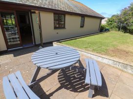 A table and benches on a patio in the garden at Yonde View in Camborne