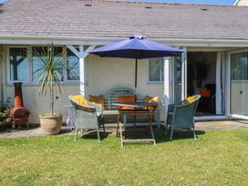 A patio area with a table and chairs under an umbrella at Rollies Retreat in Fowey