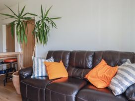 A living room with a sofa and plants at Rollies Retreat in Fowey