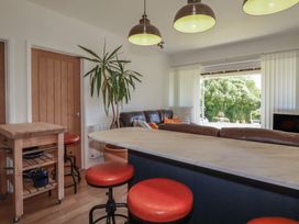A living room with a sofa and bar stools at Rollies Retreat in Fowey