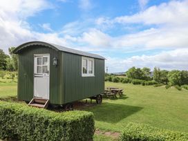 A shepherd's hut with a door and windows on a grassy area at Shepherds Hut at East Hill Pride Four Elms Hill Nr. Sidmouth