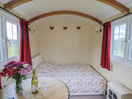 A bedroom with a bed and table with wine at Shepherds Hut at East Hill Pride Four Elms Hill Nr. Sidmouth