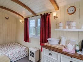 A bedroom with a bed, window, and shelf at Shepherds Hut at East Hill Pride, Four Elms Hill Nr. Sidmouth