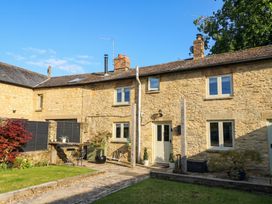 An outdoor view of a stone house with a garden at 2 The Gardens Lechlade